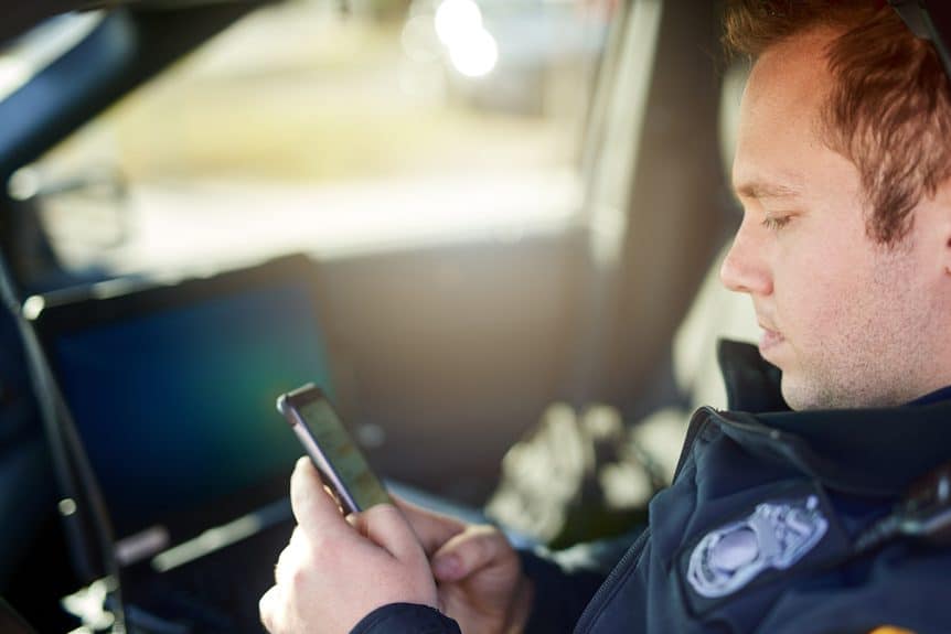 Police looking at a phone in his police vehicle