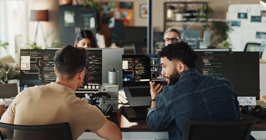 2 men infront of their computers discussing